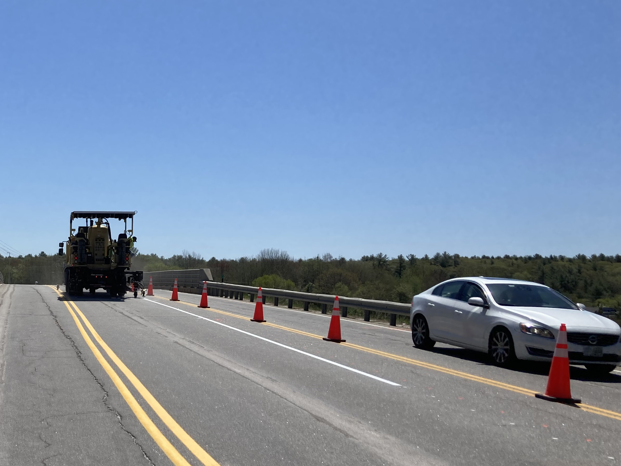 Workers use white spraypaint to indicate temporary lanes on road.